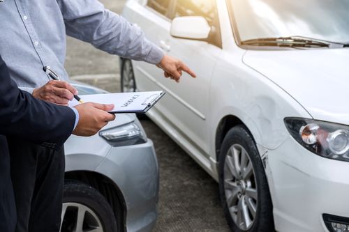 An Orlando accident attorney pointing to a dented car