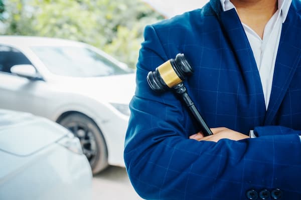 A Florida car accident lawyer stands beside a vehicle holding a gavel.
